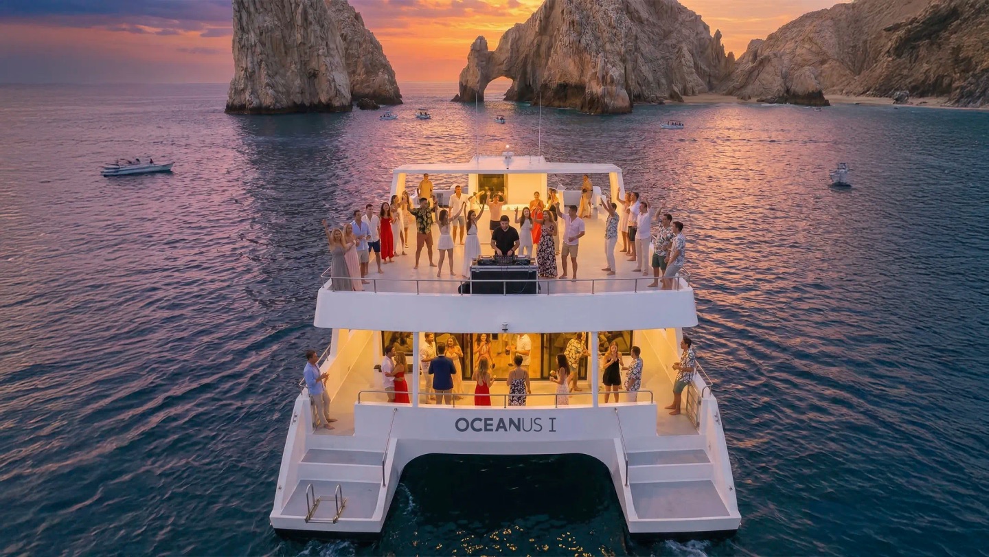 Friends enjoying sunset drinks on a Cabo cruise with ocean views